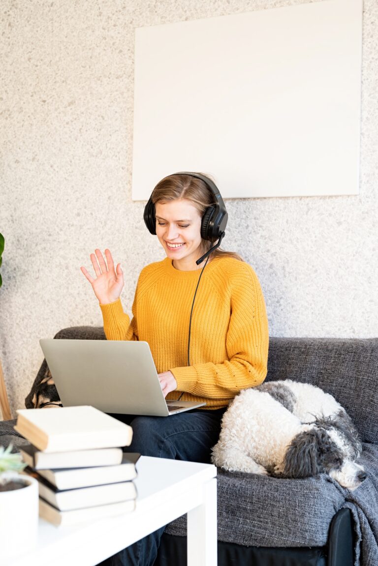 Young smiling woman in black headphones studying online using laptop